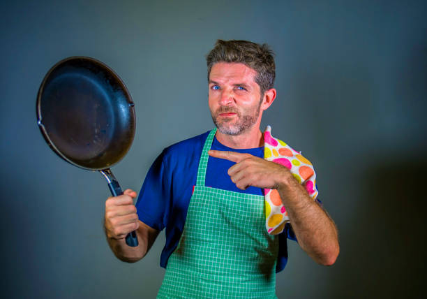 istock young attractive stressed and overwhelmed lazy man with apron holding kitchen pan in stress and frustrated face expression isolated background in domestic work and messy house husband 977554396