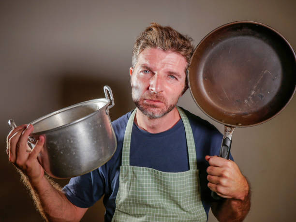 istock young attractive stressed and overwhelmed lazy man with apron holding kitchen pan in stress and frustrated face expression isolated background in domestic work and messy house husband 977554402