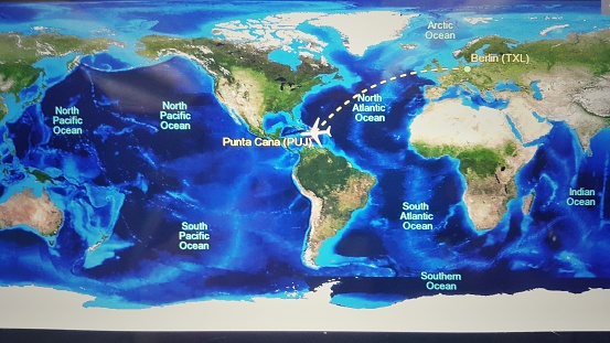 In-flight entertainment map on airplane display screen. Aircraft monitor in passenger seat shows time to arrive and travel destination.