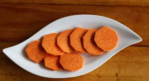 Raw sweet potatoes on wooden background closeup,food concept.