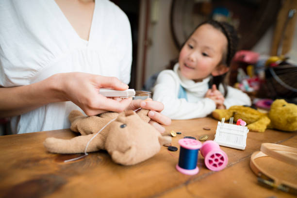istock Mother and daughter fix teddy bear 977590564