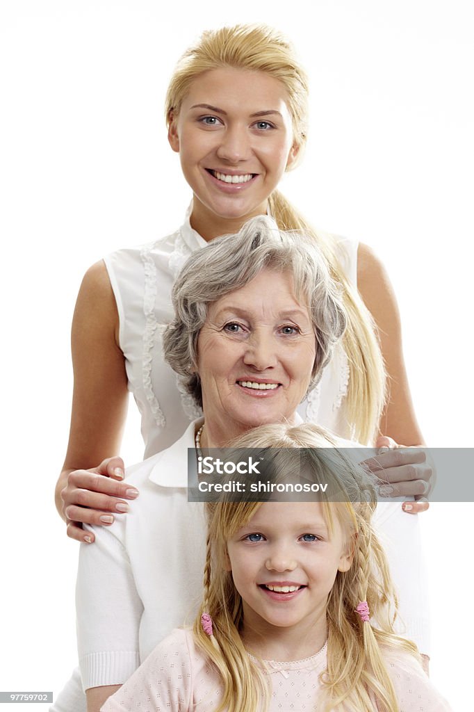 A generation of women in white standing one behind the other Row of little girl, grandmother, mother looking at camera in line Contrasts Stock Photo