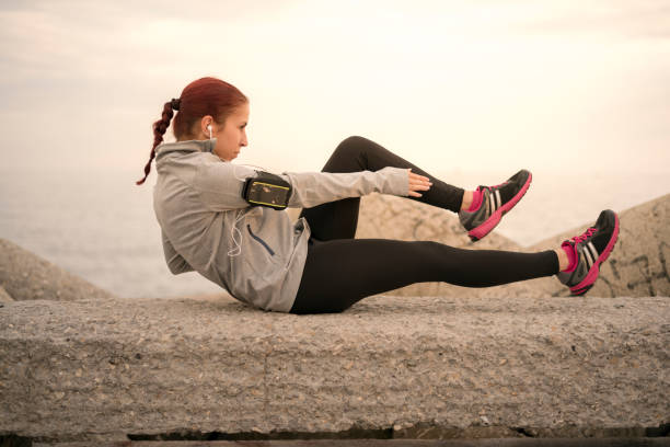 istock Sporty young woman doing crunches at the breakwater 977602206