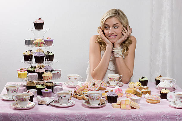 Woman with table of tea and cakes  temptation stock pictures, royalty-free photos & images