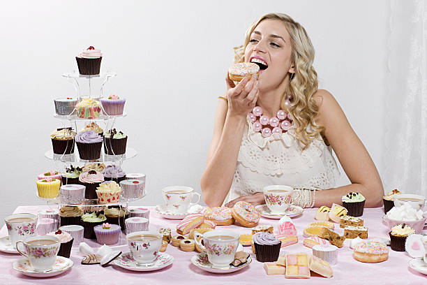 woman indulging in doughnuts and cakes - cupcake cake sweet food dessert 뉴스 사진 이미지