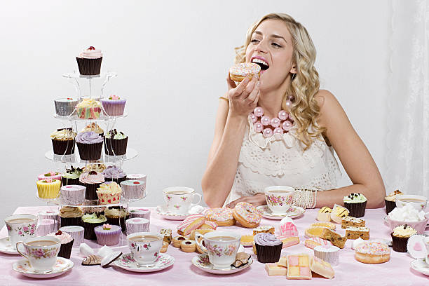 женщина, наслаждаясь в пончики и торты - excess стоковые фото и изображения