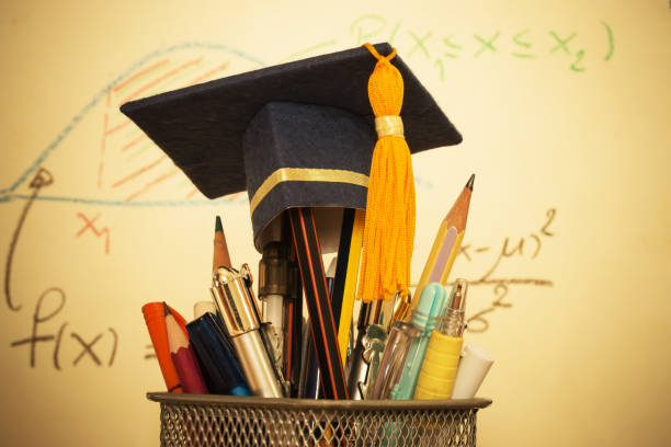 istock Education Graduate study concept: Graduation hat on pencils with formula arithmetic equation graph on projecter screen at university classroom. Ideas for knowledge learning success and Back to School 977621590