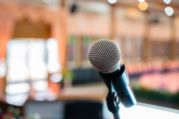 istock Microphone on abstract blurred of speech in seminar room or speaking conference hall light on stage with flower, Event Background 977621662