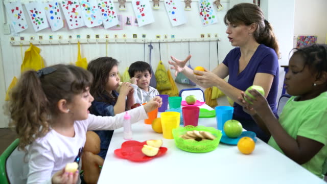 Teacher explaining fruits to students in classroom