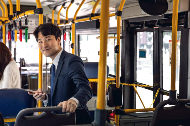 Businessman commuting by bus in Seoul - South Korea Businessman on the go in Seoul downtown commuting to work. South Korea lifestyle. seoul bus stock pictures, royalty-free photos & images