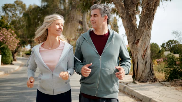 Happy mature couple jogging together on sunny day in spring