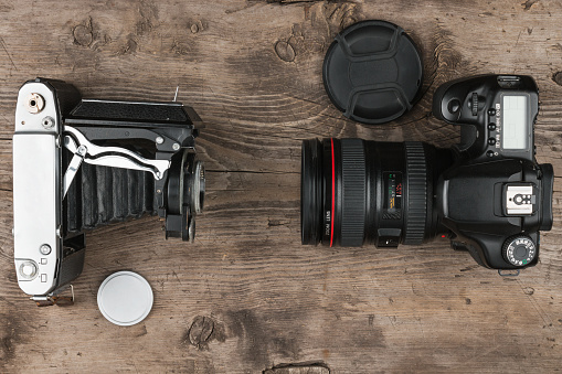 Two photo cameras on old wooden table, top view. Comparison of different generations of photographing equipment. Technology progress concept, copy space