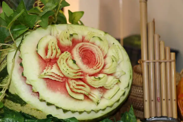 Carved fruit of watermelon to flower form and green leaves put beside Lao reed mouthorgan.