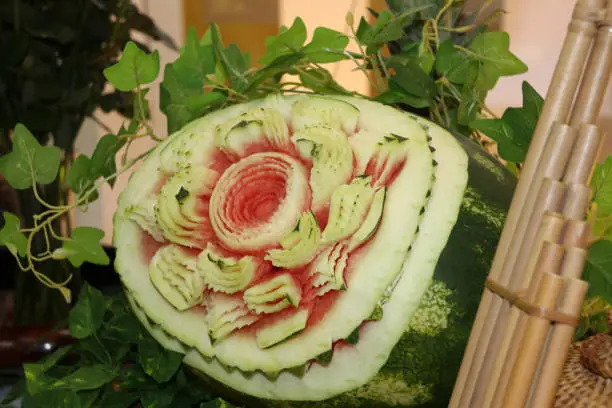 Carved fruit of watermelon to flower form and green leaves put beside Lao reed mouthorgan.