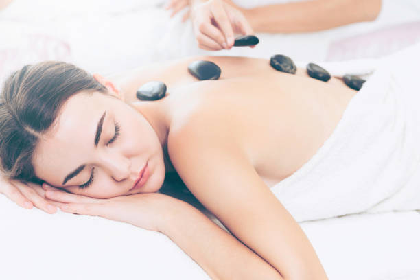 istock Hot stone massage treatment by therapist in spa. 977684340