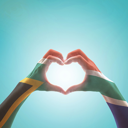 South Africa flag on woman hands in heart shape isolated on mint background for national unity, union, love and reconciliation concept