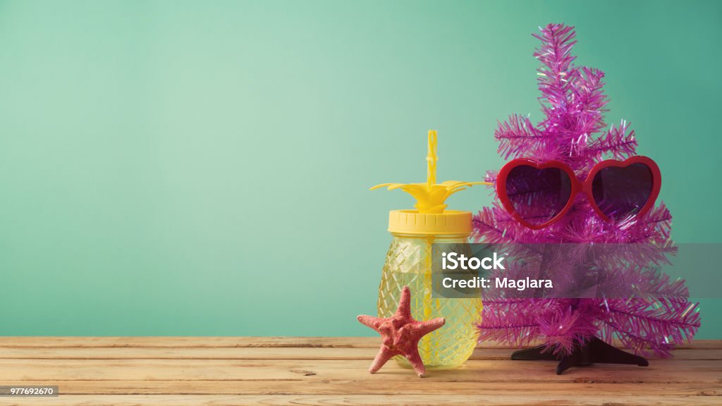 Christmas in July concept Christmas in July concept with funny christmas tree, sunglasses and pineapplle jar on table background Christmas Stock Photo