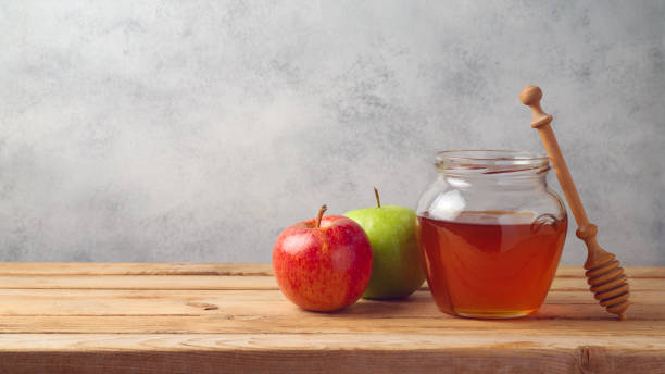 istock Honey jar and apples on wooden table 977692682