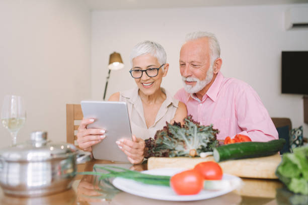 istock Senior married couple sitting on the kitchen table and looking at digital tablet 977698426