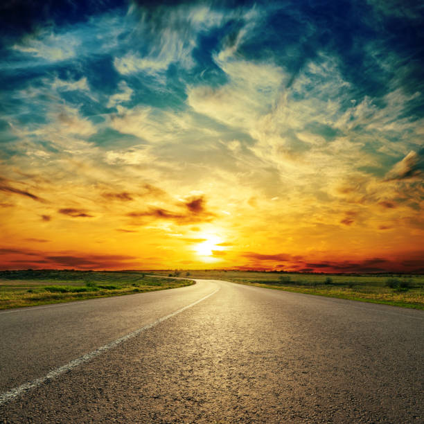 istock orange sunset in low dramatic clouds over asphalt road 977701228