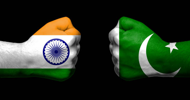 Flags of India and Pakistan painted on two clenched fists facing each other on black background/India - Pakistan relations concept stock photo