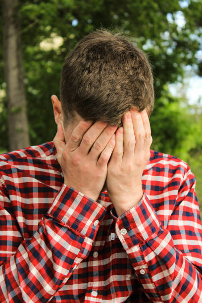 istock guy in a red shirt covers his face with his hands 977708916