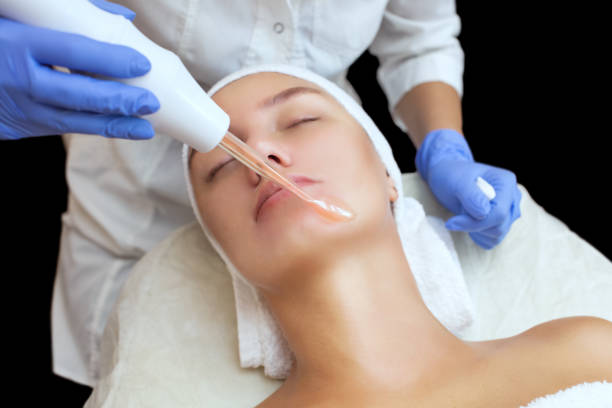 the cosmetologist makes the procedure microcurrent therapy of the facial skin of a beautiful, young woman in a beauty salon - ionization imagens e fotografias de stock