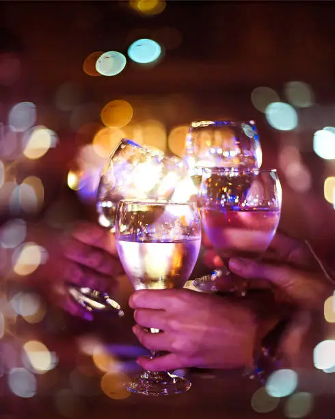 People toasting by wineglasses on dark background