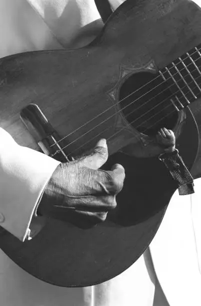 B&W photo of old man's hand playing acoustic guitar in Mexico