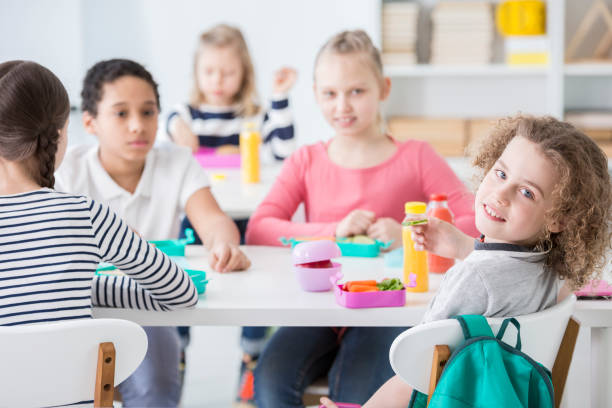 istock Happy boy eating vegetables with friends in the dining hall 977822006