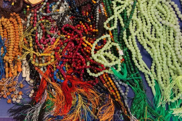 Multicolored lot of tasbeeh Tasbih beads. Huge amount of muslim prayer beads layeing on the table. Selling tasbeehs. Open air market trading with prayer beads