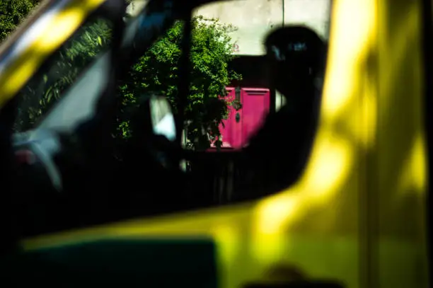 The red door appears through the window of a passing delivery van, the colours are striking, red, magenta, yellow