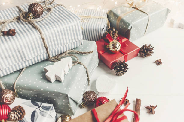 istock merry christmas concept. present boxes with ornaments tree cones anise and lights on the rustic white wooden background, space for text. seasonal greetings. happy holidays 977850202