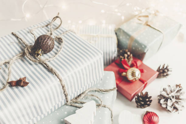 istock merry christmas concept. present boxes with ornaments tree cones anise and lights on the rustic white wooden background, space for text. seasonal greetings. happy holidays 977850414