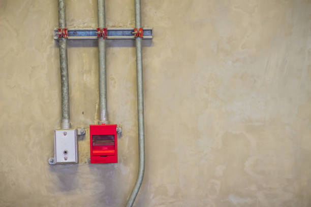 istock Red fire alarm pull box emergency and fire fighters telephone with conduit pipeline on concrete wall. 977857838