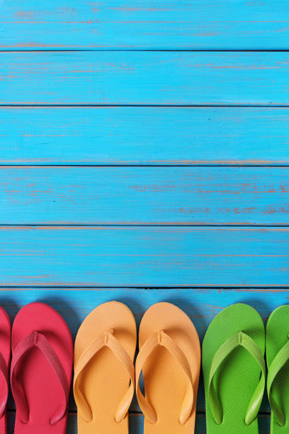 istock Flip flops in a row old weathered blue beach wood background vertical 977875386