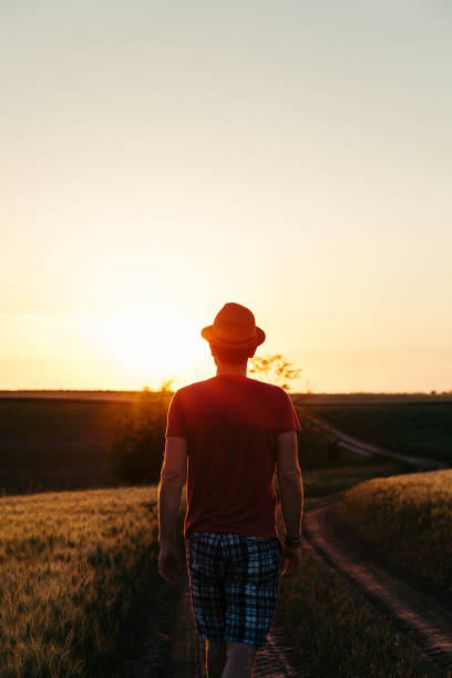istock Young man walking on the muddy road into the sunset 977882928