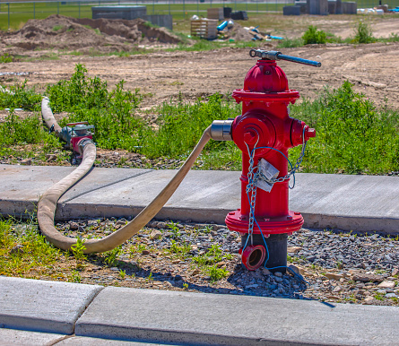 Red fire hydrant with hose connected for use in construction zone in Eagle Mountain, Utah.