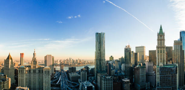 The panoramic scenic view to the Manhattan Downtown, over the Brooklyn Bridge and East River toward Brooklyn. The skyline includes the major buildings: Manhattan Municipal Building, New York by Gehry, Thurgood Marshall United Square Courthouse, Woolworth Building, One Brooklyn Bridge Plaza, and more. Aerial drone shot. la panorámica escénica a la manhattan downtown, sobre el puente de brooklyn y el río east hacia brooklyn. el horizonte incluye los principales edificios: edificio municipal de manhattan, nueva york por gehry, thurgood marshall unidos plaza del palacio d