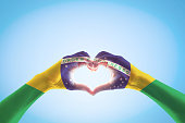 Brazil flag on people hands in heart shape for labor day and national holiday celebration isolated on blue sky background