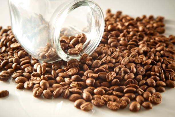 istock roasted coffee beans poured from clear glass on white background 978022720