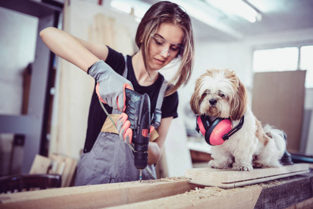 istock Female Carpenter Drilling Planks With Help From Dog Assistant 978039130