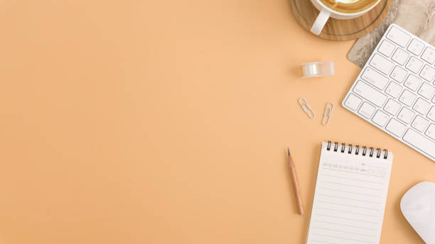 istock Flat lay, top view office table desk. Workspace with blank note book, keyboard, office supplies and coffee cup on light brown background. 978058650