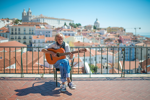 Lisbon, Portugal - June 19, 2015: Typical Fado musician singing to his guitar in front of the district of Alfama, the oldest district of Lisbon with many Fado bars and musicians performing the traditional Portuguese folk music.