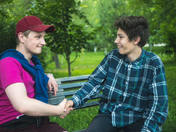 istock two young smiling friends handshake sitting on the bench outdoors on a summer day 978179328