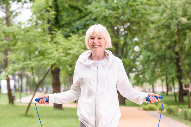 istock smiling elderly sportswoman with jump rope in park 978208312
