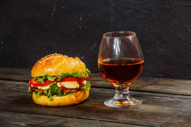 istock Hamburger on a wooden board against a dark background with copy space. Hamburger with sauce and fresh vegetables on a wooden table. Burger. 978216202