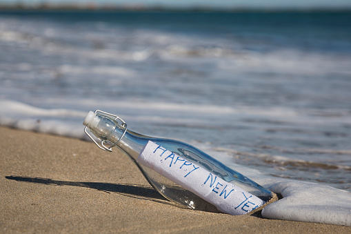 Close up of a bottle at the beach containing a message of Happy New Year.