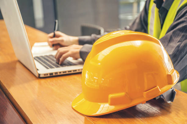 istock The yellow safety helmet and Business man in Construction industry is taking note on computer on the background 978238344