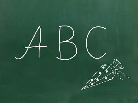 The letters ABC handwritten with chalk on a green chalkboard.